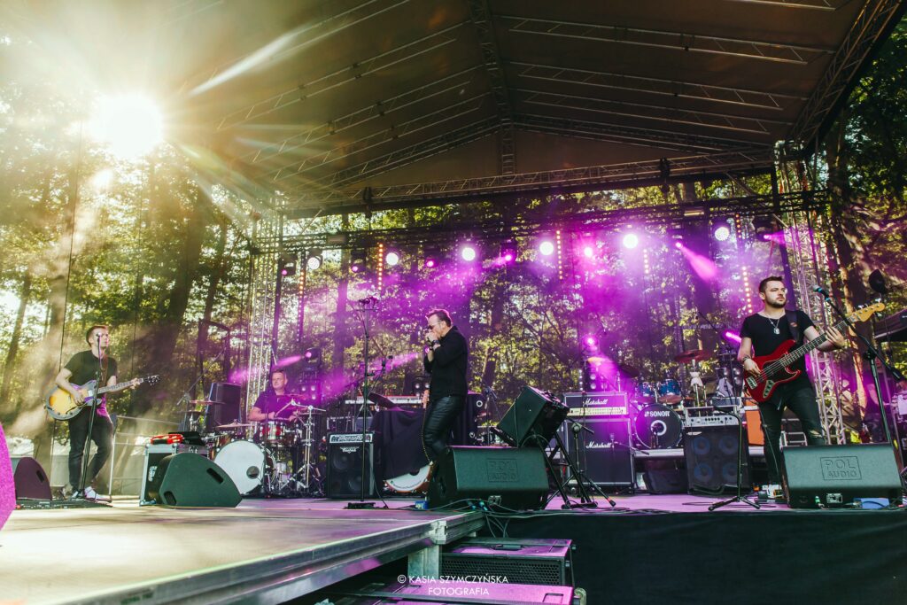 Koncert plenerowy z oświetloną sceną i muzykami