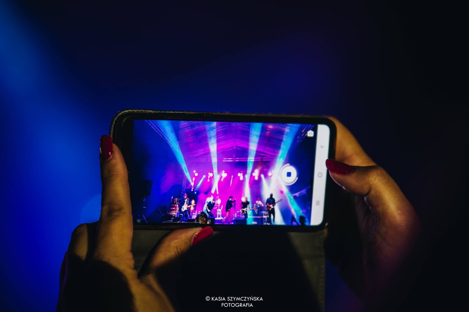 Koncert widziany na ekranie telefonu wśród publiczności